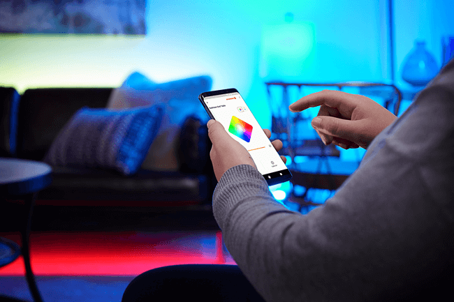 Person sitter med appen åpen på en smarttelefon, klar til å styre lyset