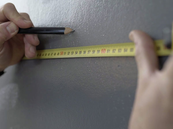Bredden på veggen måles og det lages markeringer for hver tapetbane